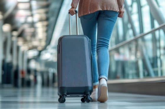 Woman walking in an airport with a carry-on suitcase